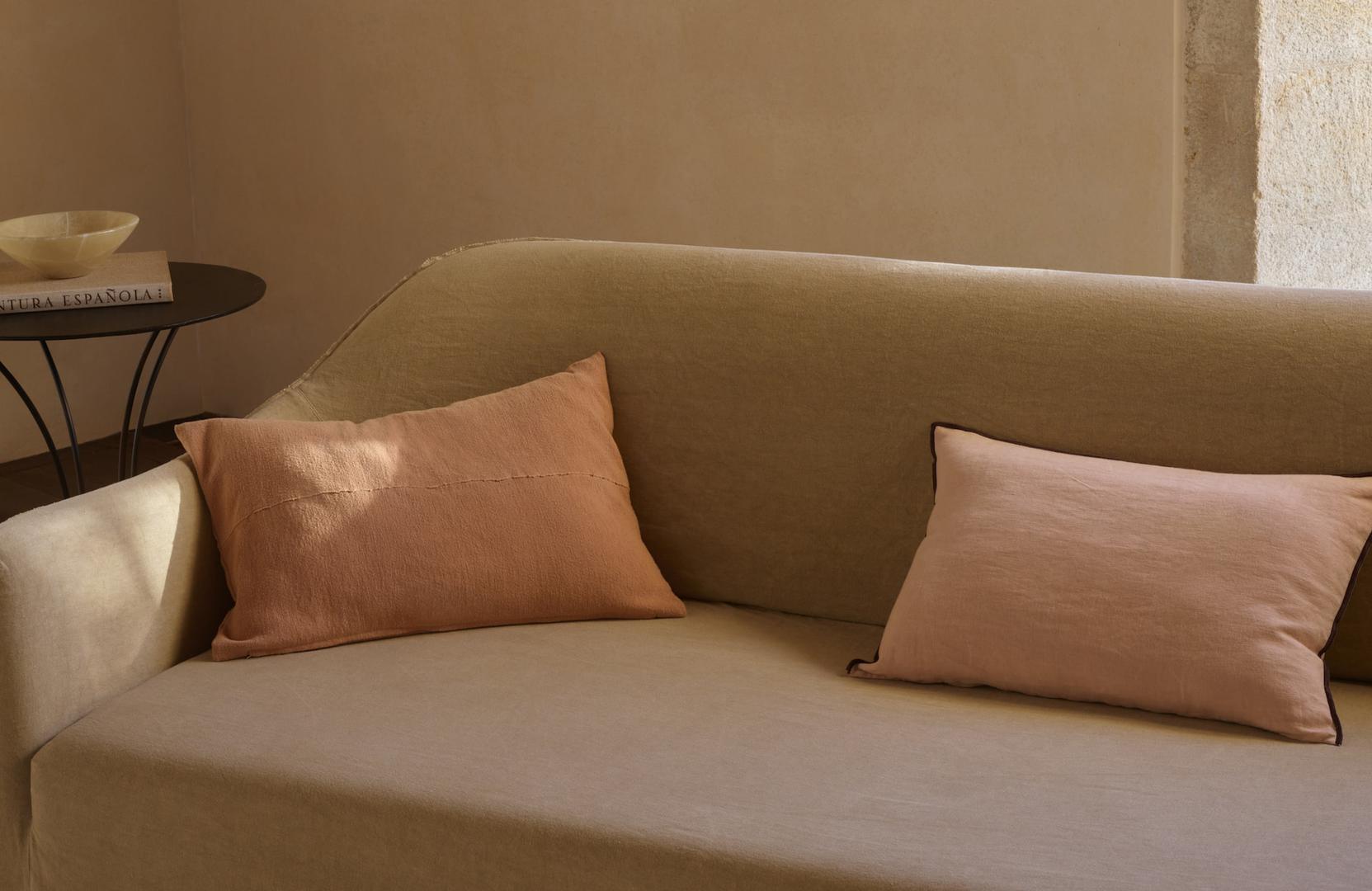 Mekana sofa u neutralnim tonovima razigrana je mekanim pink jastucima
