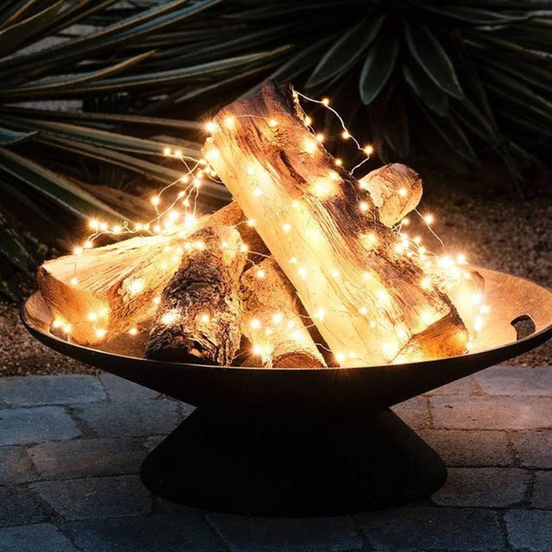 Stvorite dojam vatrice uz pomoć lampica koje ćete omotati oko lijepo posloženih cjepanica u elegantnoj posudi